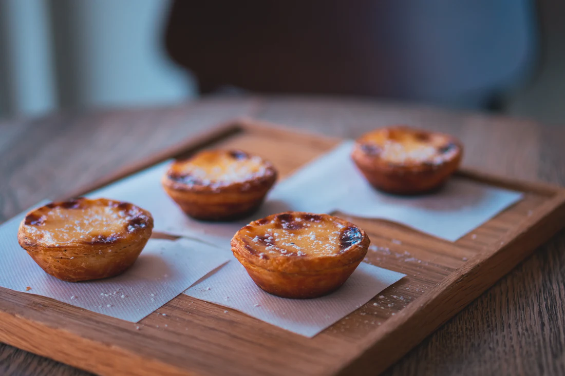 Four pastéis de nata on a wooden board