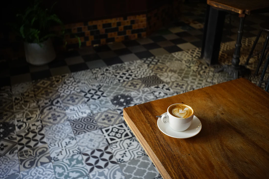 Patterned floor tiles beside a table with a coffee cup