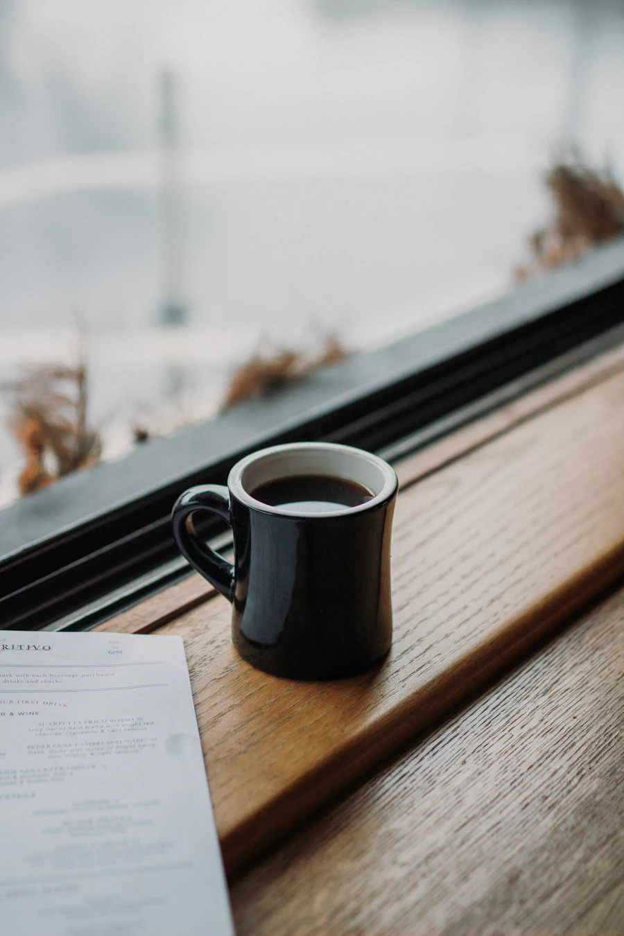 Black mug of coffee on a window ledge